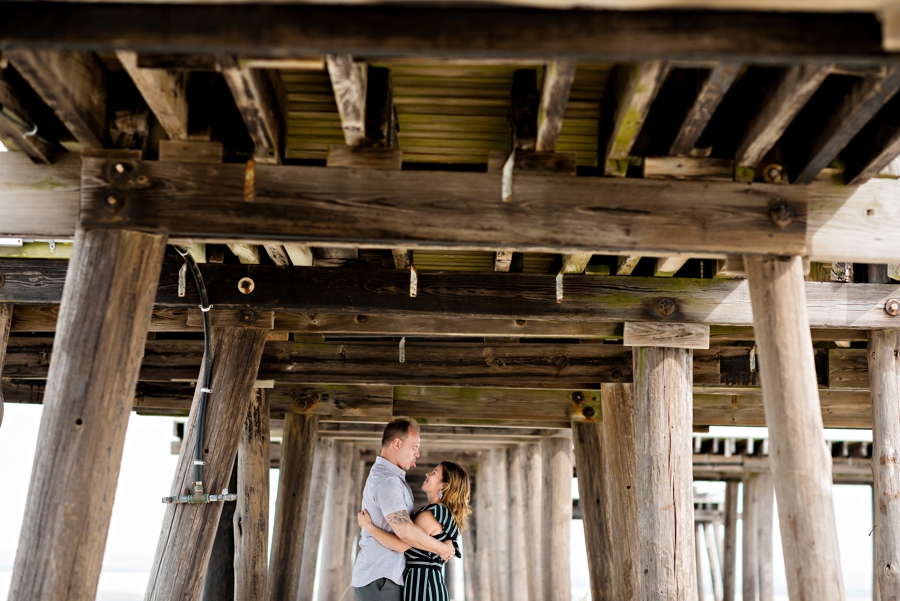 An engaged couple under the pier in Wildwood, nj.
