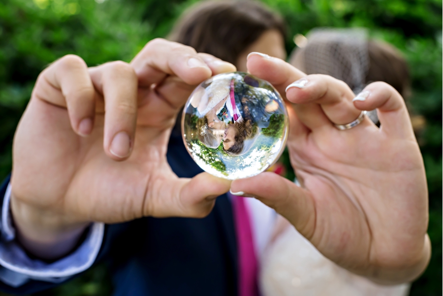 The reflection of a bride and groom kissing in a crystal ball.
