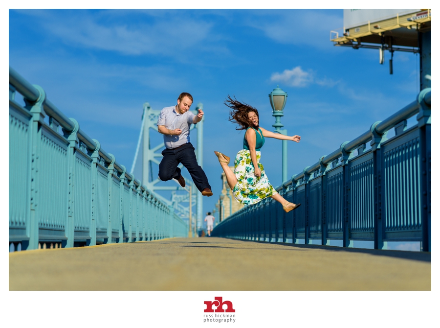 A couple on the Ben Franklin Bridge jumping during their Philadelphia Engagement Session