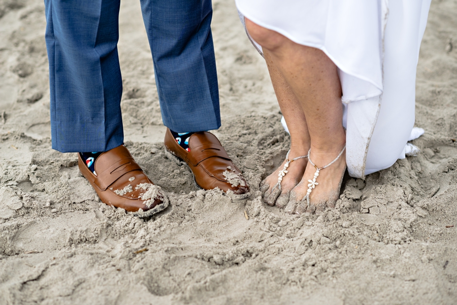 A newly married couple with their feet in the sandy beaches of cape may.
