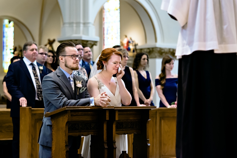 A bride and groom cry during their catholic ceremony.