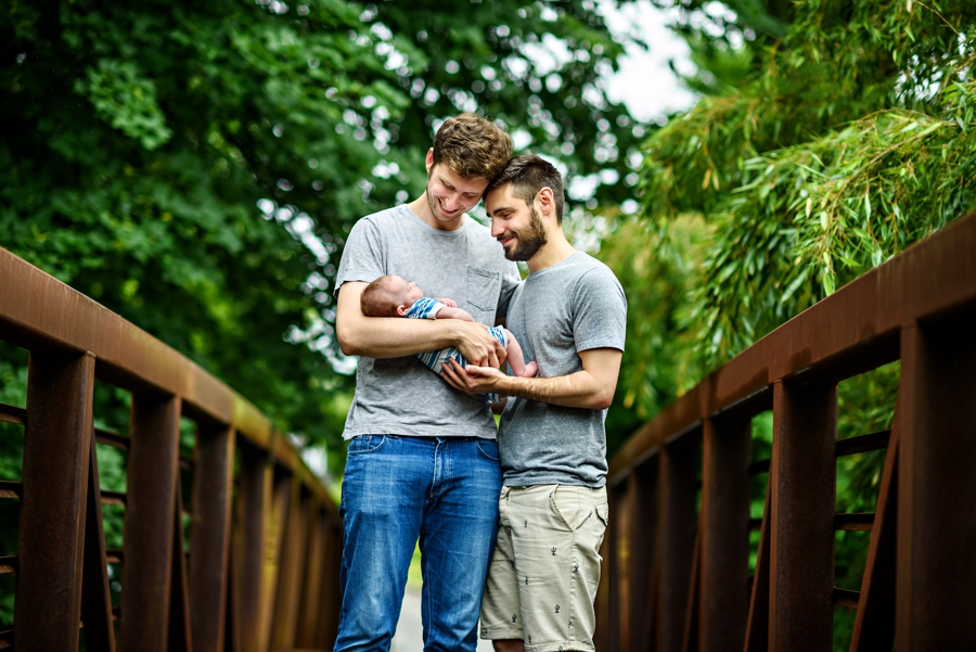 Two Fathers hold their newborn baby girl in their arms during a family photography session.