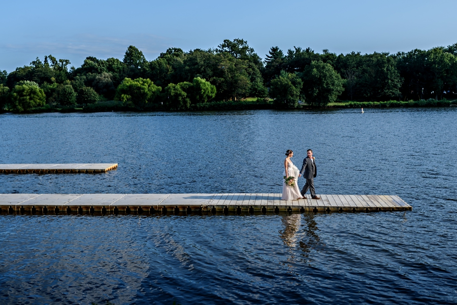 A married couple walk to the end of the dock on their wedding at the Camden County Boathouse in Pennsauken, NJ.