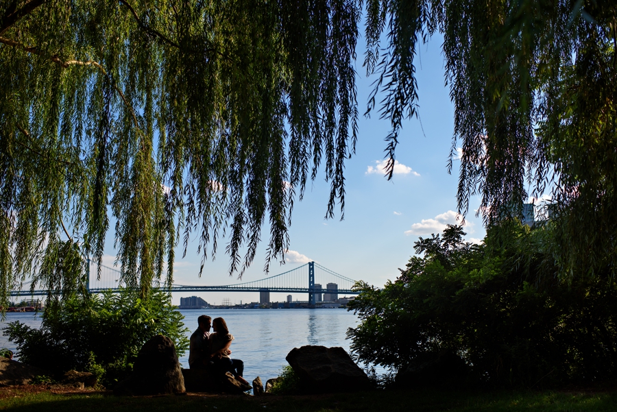 A silhouette of a couple in Penn Treaty Park with the Ben Franklin Bridge in the background during their Philadelphia Engagement Session.