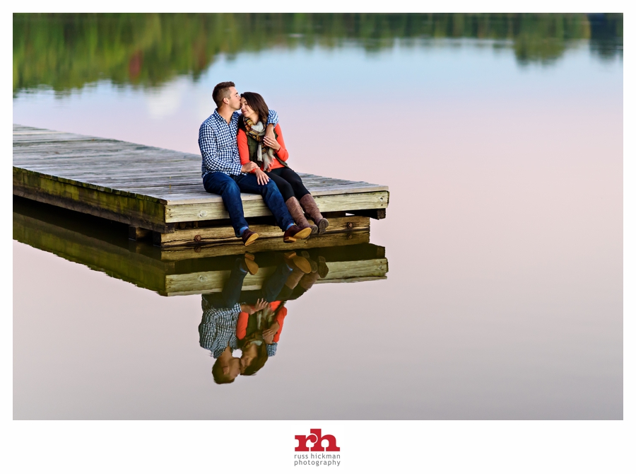 A gorgeous couple sit on the end of a dock and enjoy the sunset in their Lums Pond State Park Engagement Session.