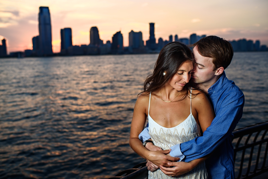 A man kisses his bride to be along the river walk in Battery Park during their NYC Engagement Session.