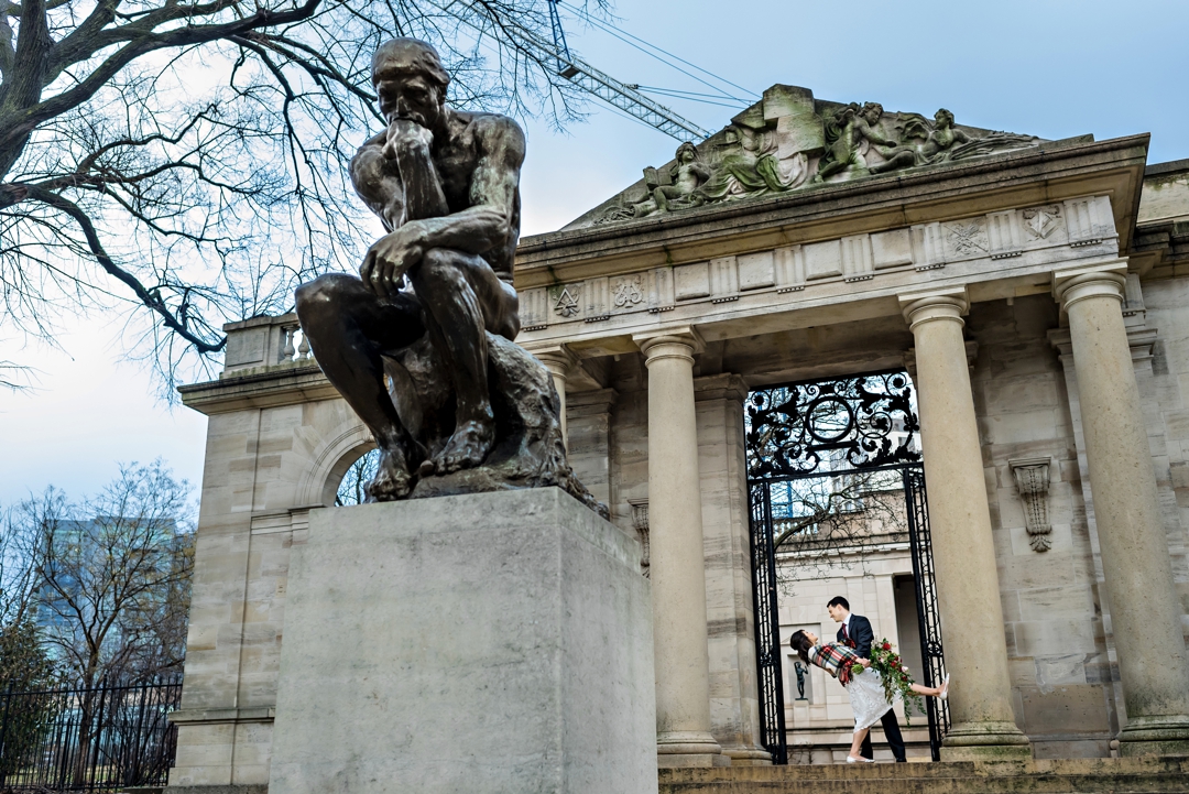 A newly married couple dance in front of the gates at the Rodin Museum on their wedding day.