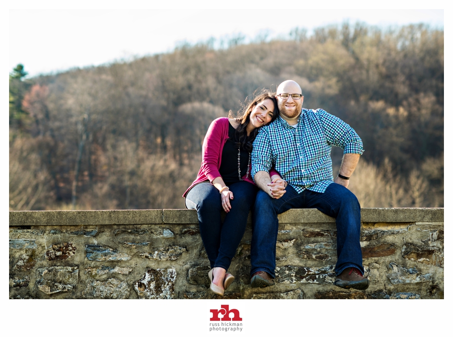 A couple cuddle next to each other during Valley Forge Park Engagement Session.