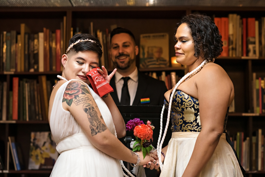 A bride wipes away a tear during her wedding ceremony at the housing works bookstore in NYC.
