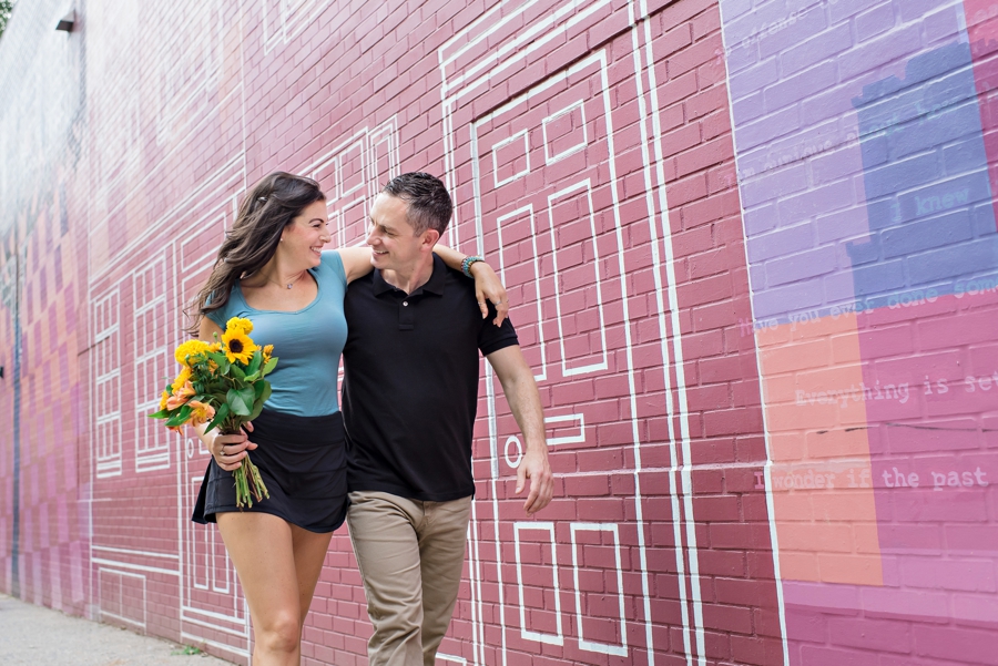 An engaged couple walk with their arms around each other in Philadelphia.
